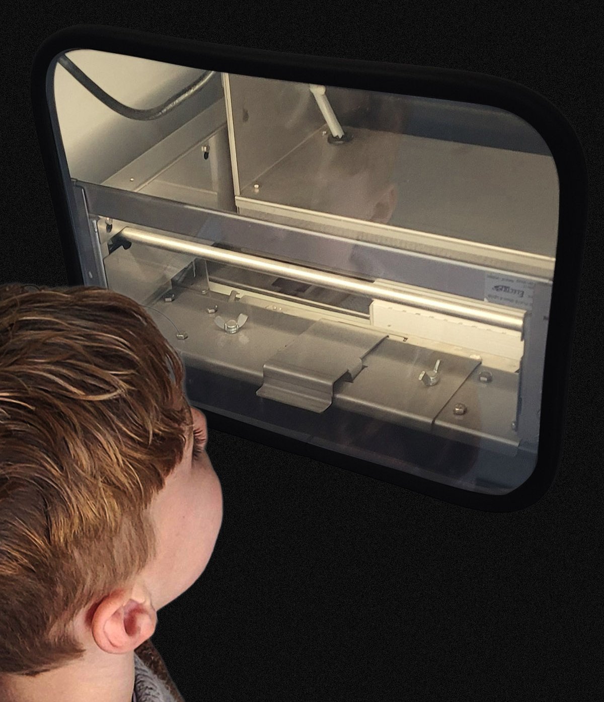 A child watching the arm and oven through the kiosk window